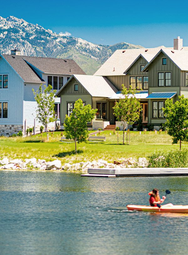 A Rainey Home on the Island in Daybreak, UT with the snowy Wasatch Mountains in the background and a kayaker the Oquirrh Lake.